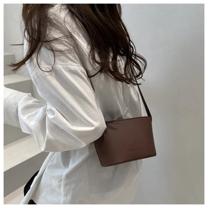 Détail d'un sac seau en cuir marron foncé avec embossage élégant de la marque