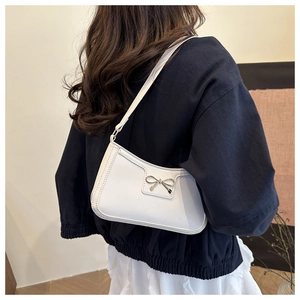 Dettaglio della borsa sottobraccio in ecopelle bianca con fiocco dorato e tracolla sottile