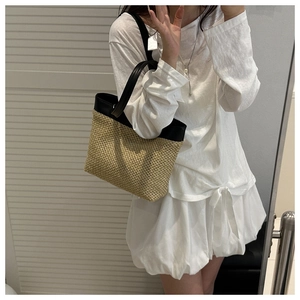 Mirror selfie showing the large straw woven tote bag size with black leather trim detail