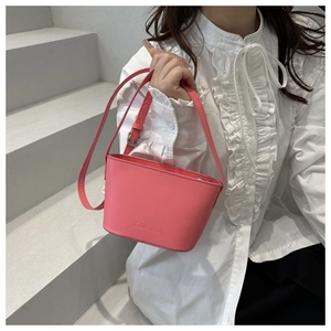 Gros plan d'un sac seau en cuir rose porté par un mannequin sur fond de pierre