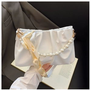 Detail of white pleated cloud bag featuring pearl chain and silk-wrapped shoulder strap