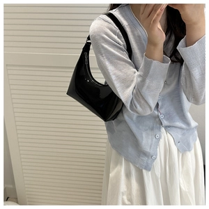 Chic black patent leather hobo bag with glossy finish shown on model in modern setting