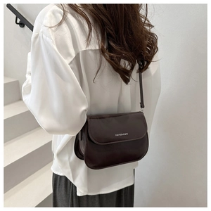 Detail of dark brown leather saddle bag featuring a minimalist matte finish and fine stitching