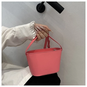 Détail du sac seau rose vif avec logo embossé et poignée assortie élégante