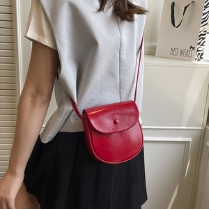 Minimalist bright red saddle bag crossbody on model with sleek glossy leather finish
