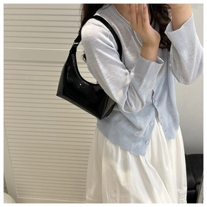Close-up of black glossy patent leather hobo bag on shoulder for a chic summer look