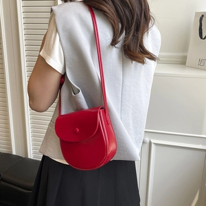 Red PU leather saddle bag crossbody worn by model in a minimalist modern interior