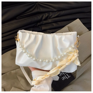 Close-up of a white ruched cloud bag featuring a pearl handle and silk scarf detail