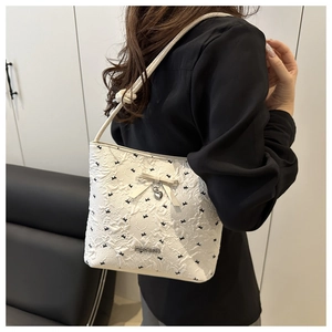 Detail of white embossed shoulder bag with black butterfly patterns and bow charm decor