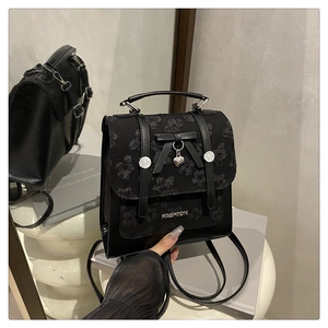 Détail du sac à bandoulière en dentelle noire avec fermoir papillon et pendentif cœur