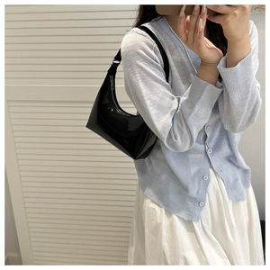 Detail view of a black patent leather crescent shoulder bag with high-gloss finish