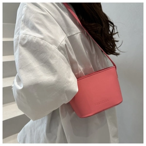 Pink matte leather bucket bag with debossed logo shown on a white staircase model