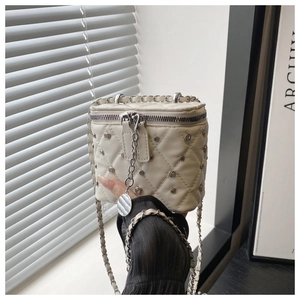 Detailed view of white quilted crossbody bag with silver studs and chain strap