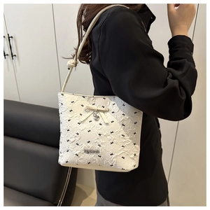 Detail of white embossed shoulder bag with small black bows and heart pendant