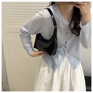 Glossy black patent leather hobo bag worn on shoulder for a chic retro aesthetic look