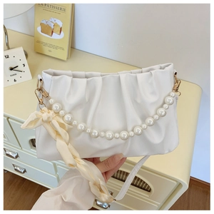 Detail of white pleated cloud bag with pearl handle and silk scarf accessory