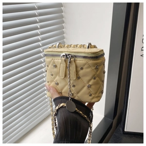 Close-up of light yellow quilted crossbody bag with sparkling rhinestones and chain strap