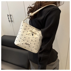 Detail of white textured bucket bag with black bow embroidery and heart charm