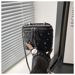 Close-up of mini black quilted crossbody box bag with silver studs and chain strap