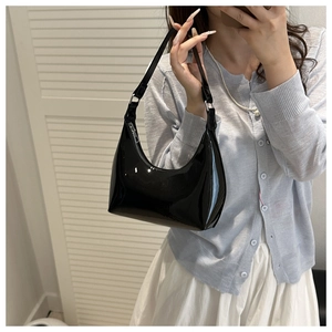 Black glossy patent leather hobo bag worn by model, showing size and mirror-like finish