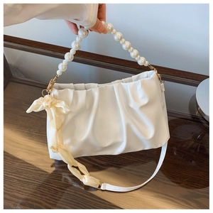 Detail of white ruched cloud bag featuring pearl handle and decorative yellow silk scarf