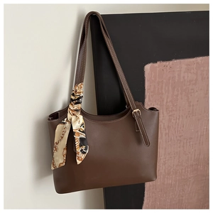 Close-up of brown tote bag with white contrast stitching and printed silk scarf on handle