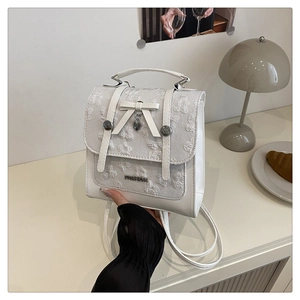 Detail view of white PU leather backpack with bow, heart pendant and floral texture