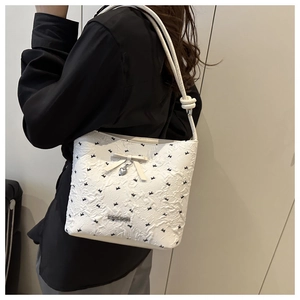 Close-up of white bucket bag featuring rabbit patterns, bow, and heart pendant