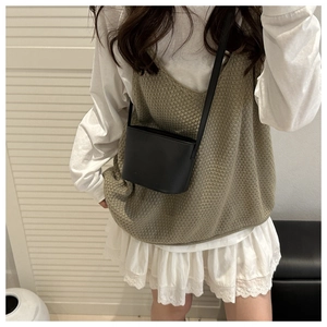 Détail d'un petit sac seau noir en cuir mat porté avec une tenue décontractée