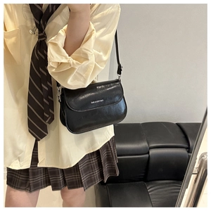 Detail view of a black flap crossbody bag with FANYISSA & BAG lettering and adjustable strap