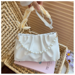 Detail of white pleated cloud bag featuring large pearls and silk scarf handle decor
