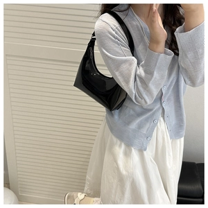 Glossy black patent leather crescent shoulder bag styled with a casual outfit
