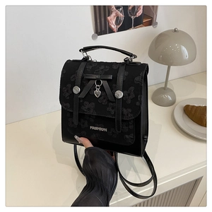 Close-up of black leather backpack with embossed floral pattern and heart pendant