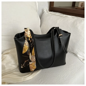 Detail of black tote bag featuring white contrast stitching and yellow floral silk scarf