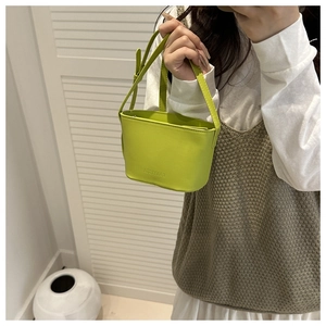 Détail d'un mini sac seau vert néon avec logo embossé et bandoulière en cuir réglable