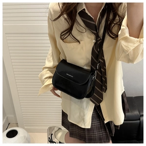 Close-up of black leather crossbody bag with white logo lettering on a female model