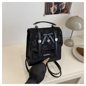 Detail of black mini backpack with lace floral embroidery and butterfly heart charm