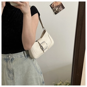 Detail of white leather baguette bag with large silver buckle shown in a mirror selfie