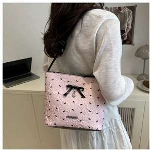 Detail of pink textured bucket bag featuring black bow prints and a silver heart pendant