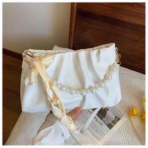Detail of white pleated cloud bag featuring pearl chain strap and satin silk scarf