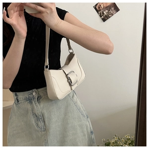 Close-up of cream underarm bag featuring a stylish silver metal buckle and sleek leather finish