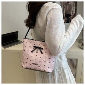 Detail of pink pleated bucket bag with bow patterns and metallic fashion plaque