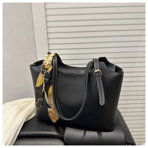 Close-up of black tote bag featuring white contrast stitching and a floral silk scarf