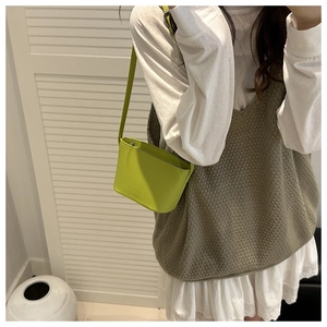 Close-up of bright green leather bucket bag featuring embossed text and slim strap