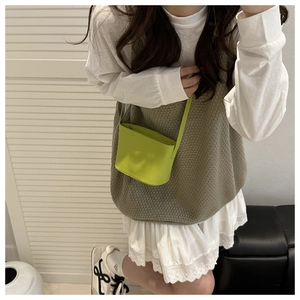 Gros plan sur un mini sac seau vert fluo avec fermeture éclair porté par un mannequin