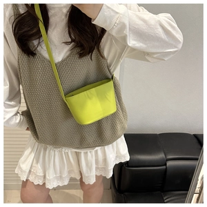 Détail du mini sac seau vert néon avec lettrage embossé sur une finition en cuir texturé