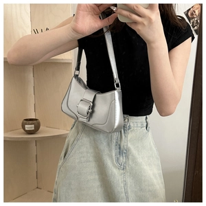 Detail of silver metallic underarm bag with metal buckle shown on a model