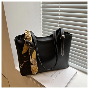 Detail of black leather tote bag with white stitching and decorative floral silk scarf