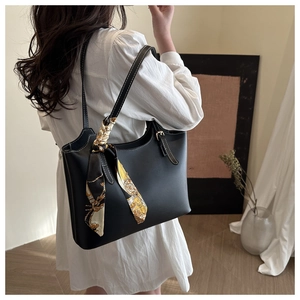 Detail of black leather tote bag featuring white contrast stitching and silk scarf wrap