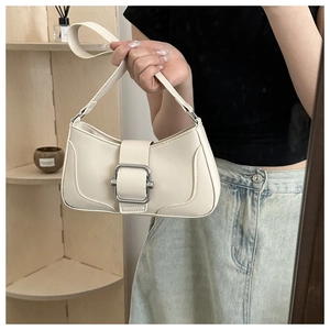 Detail view of cream shoulder bag featuring a large silver metal buckle and smooth leather